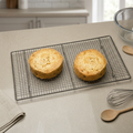 Cooling rack with two sponge cakes on a kitchen worktop beside baking accessories