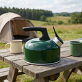 Green camping kettle on a picnic table at a campsite