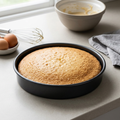 Sandwich cake tin with a freshly baked sponge on a kitchen worktop