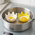 Silicone egg poachers floating in a saucepan